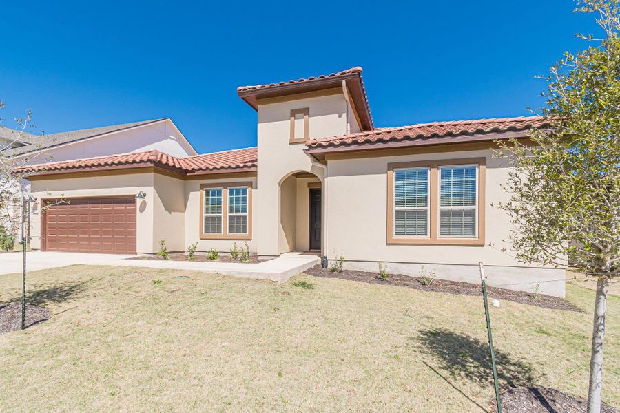 Mediterranean / spanish home with a front yard, concrete driveway, an attached garage, and stucco siding