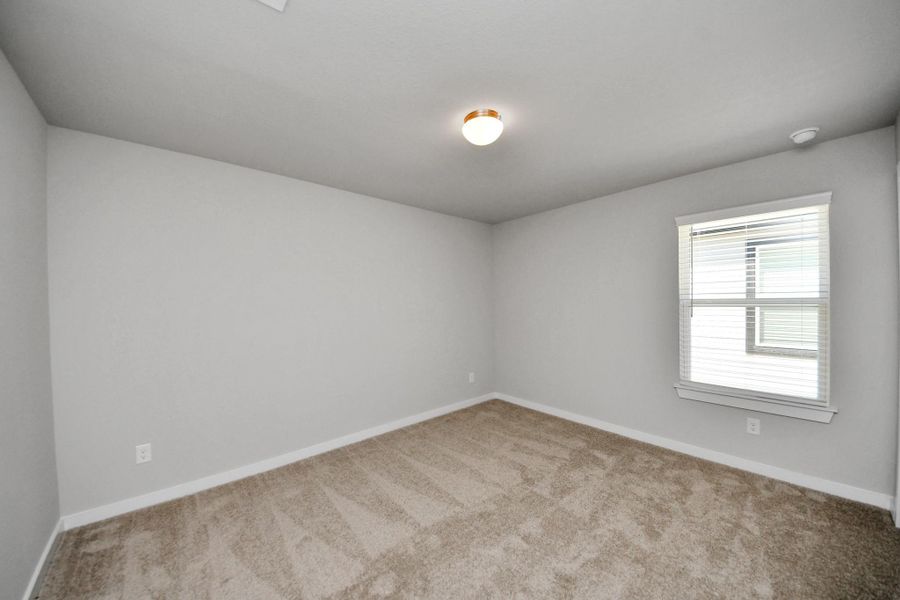 Secondary bedroom features plush carpeting, large windows that let in plenty of natural light, bright paint, and spacious closets. Sample photo of completed home with similar floor plan. Actual colors and selections may vary.