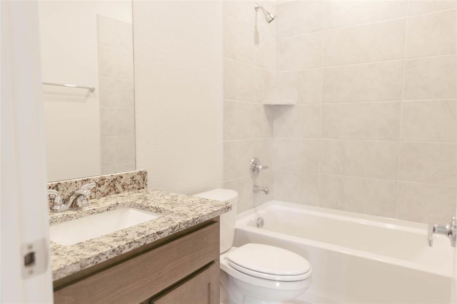 Full bathroom with tiled shower / bath combo, toilet, and vanity