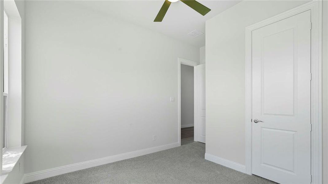 Unfurnished bedroom with light colored carpet and ceiling fan