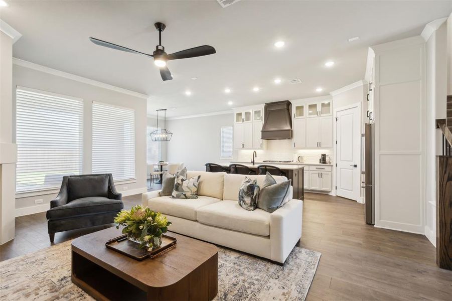 Living room with ceiling fan, crown molding, and light hardwood / wood-style floors