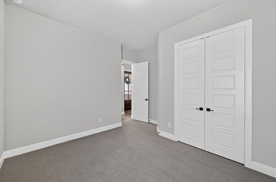 Room featuring light grey wall paint, plush grey carpeting, white baseboards, and white trim Room featuring light grey wall paint, plush grey carpeting, white baseboards, and white trim