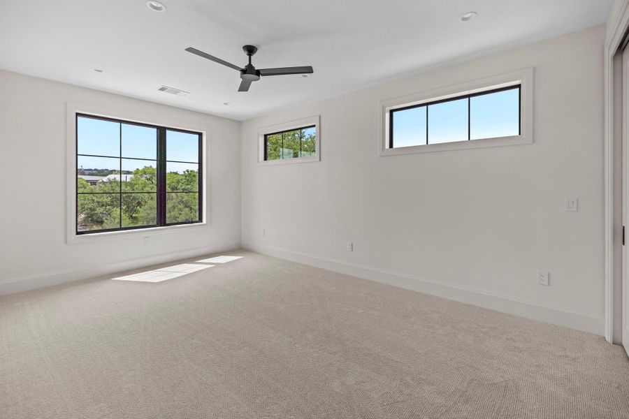 Carpeted empty room with ceiling fan and baseboards
