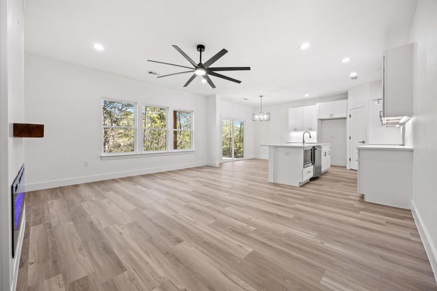Unfurnished living room with a chandelier, light wood-style floors, and ceiling fan