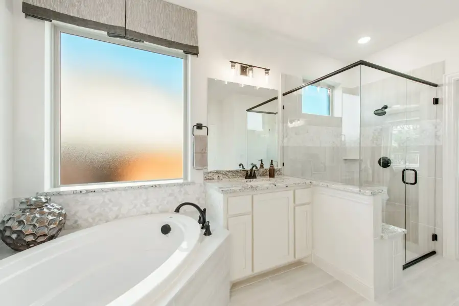 Master bathroom with soaking tub, glass walk-in shower, white vanity, and granite countertops