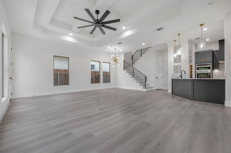 Unfurnished living room featuring recessed lighting, light wood-style flooring, a ceiling fan, stairway access, and classic baseboards. Unfurnished living room featuring recessed lighting, light wood-style flooring, a ceiling fan, stairway access, and classic baseboards.