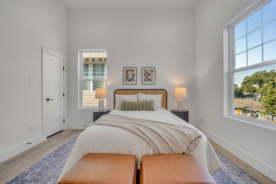 Bedroom with light hardwood / wood-style floors and multiple windows