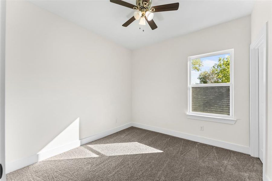Empty room featuring dark colored carpet and a ceiling fan Empty room featuring dark colored carpet and a ceiling fan