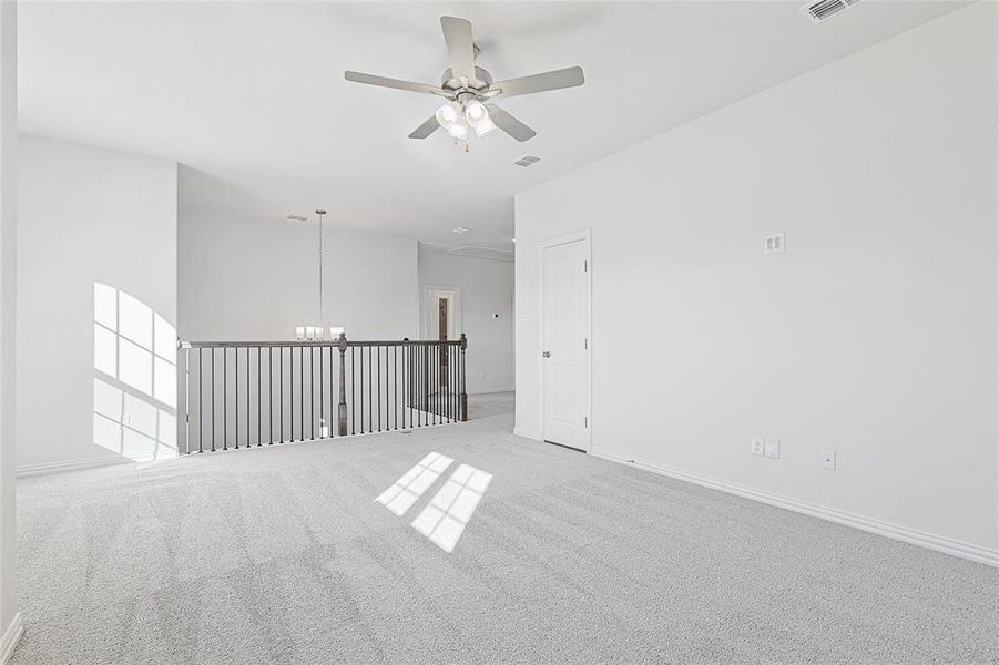 Carpeted spare room with ceiling fan with notable chandelier