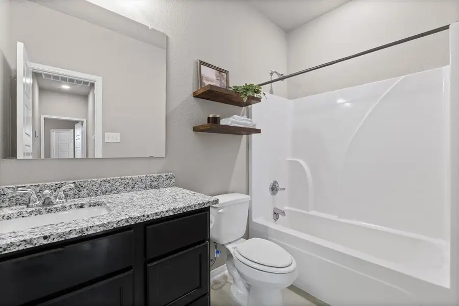 Full bathroom featuring shower / tub combination, vanity, and a textured wall Full bathroom featuring shower / tub combination, vanity, and a textured wall