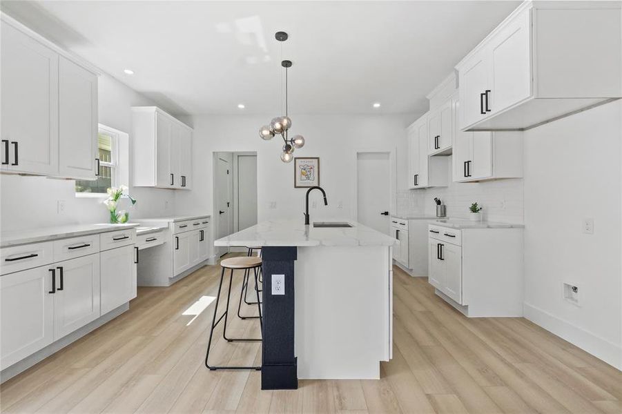 Kitchen with white cabinets, decorative backsplash, light wood finished floors, a breakfast bar area, and recessed lighting Kitchen with white cabinets, decorative backsplash, light wood finished floors, a breakfast bar area, and recessed lighting