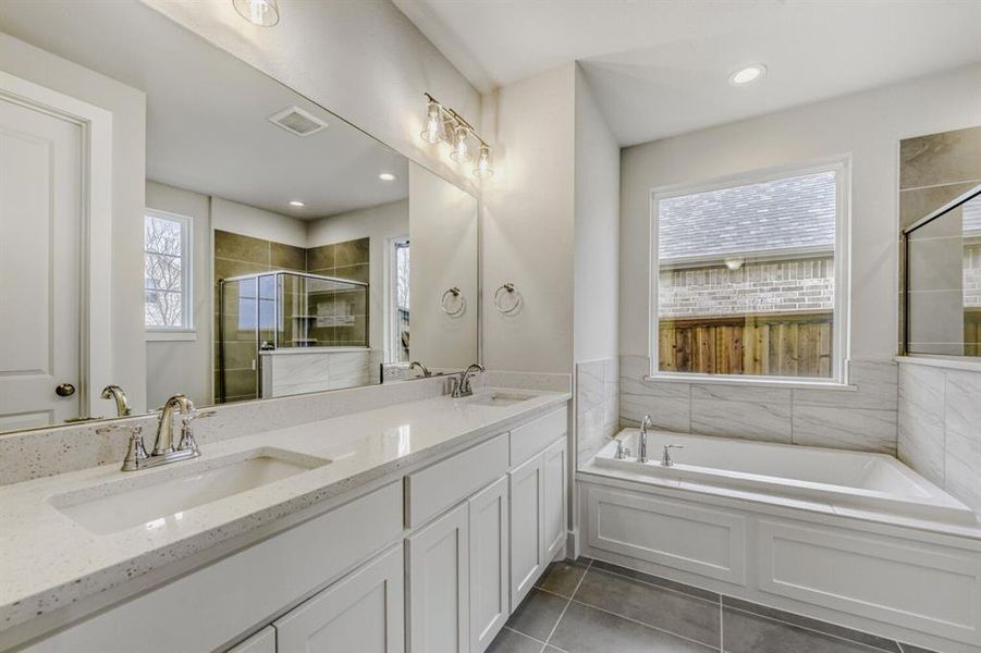 Bathroom featuring double vanity, a bath, dark tile patterned floors, a tile shower, and recessed lighting