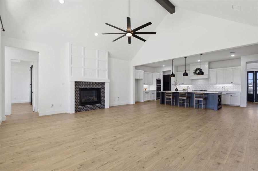 Living room featuring ceiling fan, beamed ceiling, high vaulted ceiling, a fireplace, and light hardwood / wood-style floors