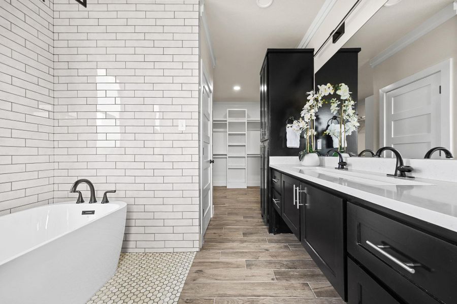 Bathroom featuring a soaking tub, vanity, a spacious closet, recessed lighting, and wood tiled floors Bathroom featuring a soaking tub, vanity, a spacious closet, recessed lighting, and wood tiled floors