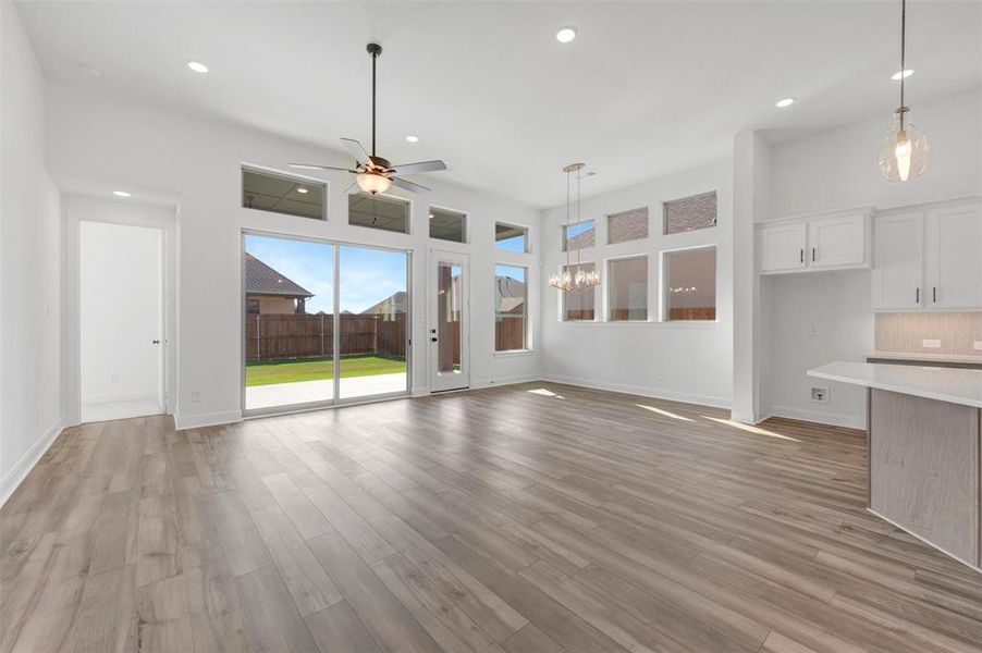 Spacious living area featuring wood-finish flooring, recessed lighting, and a ceiling fan Spacious living area featuring wood-finish flooring, recessed lighting, and a ceiling fan