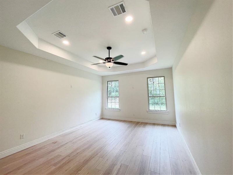Primary suite that overlooks the back yard, trayed ceilings, plenty of lighting and a convenient fan
