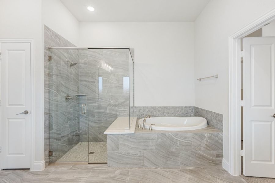 Master bathroom with glass-enclosed shower and soaking tub surrounded by gray marble tile Master bathroom with glass-enclosed shower and soaking tub surrounded by gray marble tile