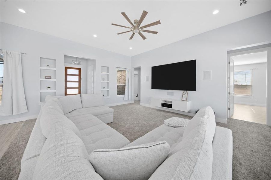Carpeted living room with built in features, a ceiling fan, and recessed lighting