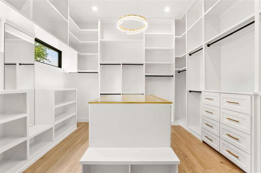 Custom closet system featuring extensive shelving, hanging rods, and built-in drawers with gold-tone hardware