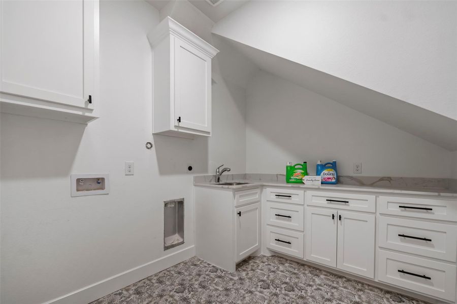 Spacious laundry room with ample storage, sleek countertops, and a convenient wash station.