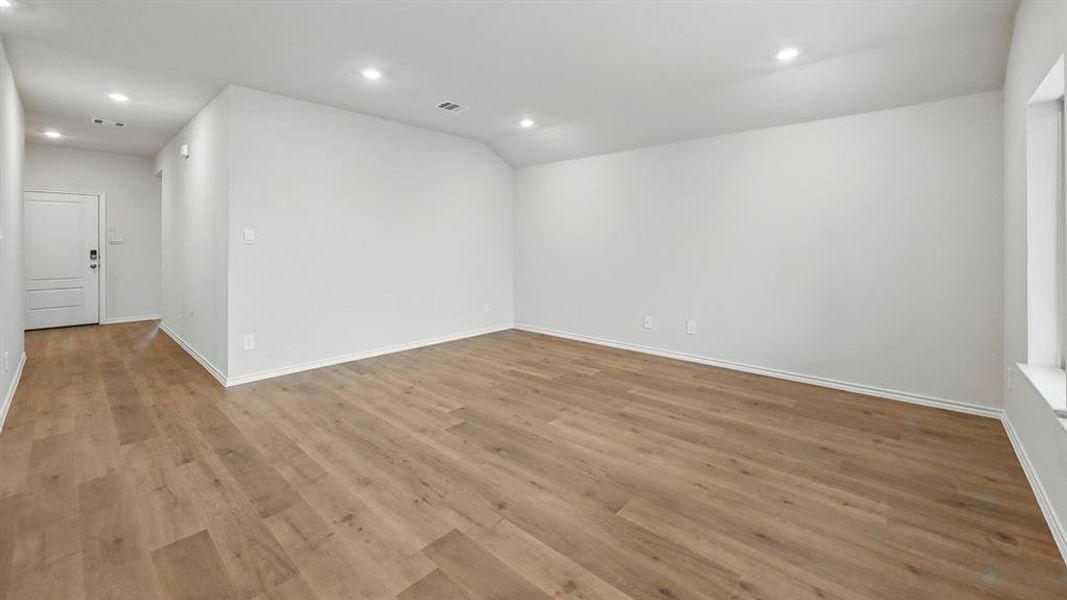 Unfurnished room featuring recessed lighting, wood finished floors, and lofted ceiling