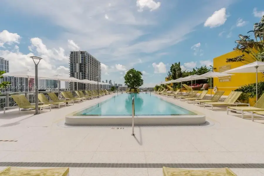 Rooftop swimming pool featuring a tiled deck, metal handrail, and integrated landscaping Rooftop swimming pool featuring a tiled deck, metal handrail, and integrated landscaping