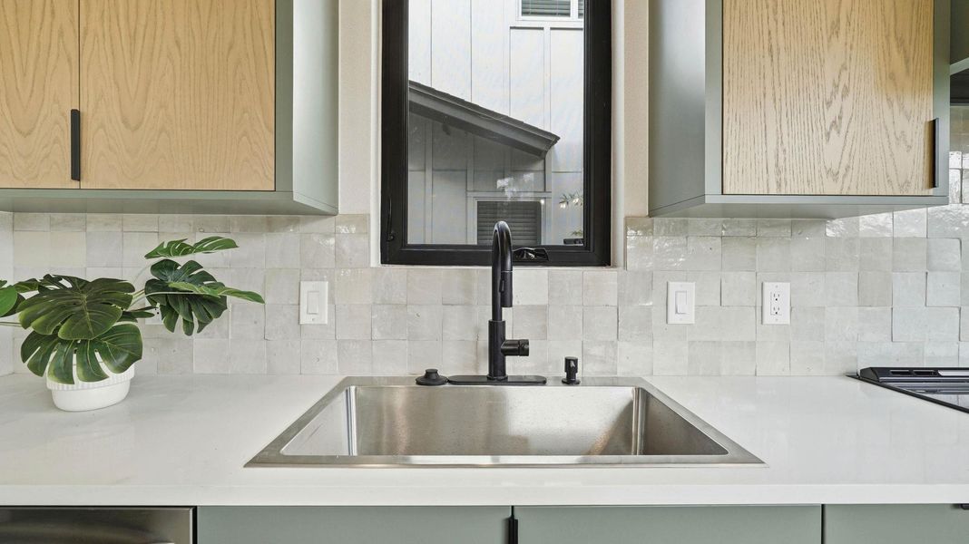 Kitchen view of light stone counters, backsplash, and dishwasher