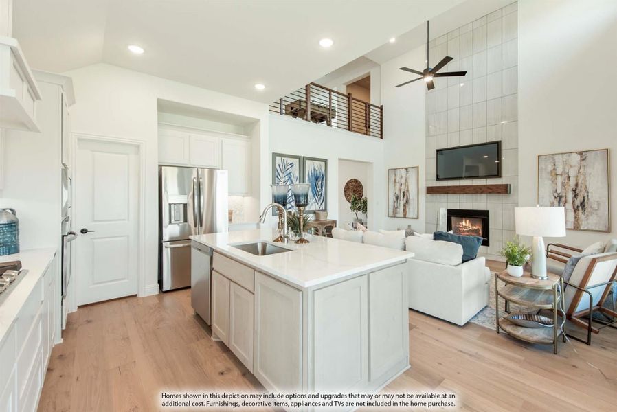 Open-concept kitchen with white island and quartz countertop flowing into living room with two-story ceiling and fireplace