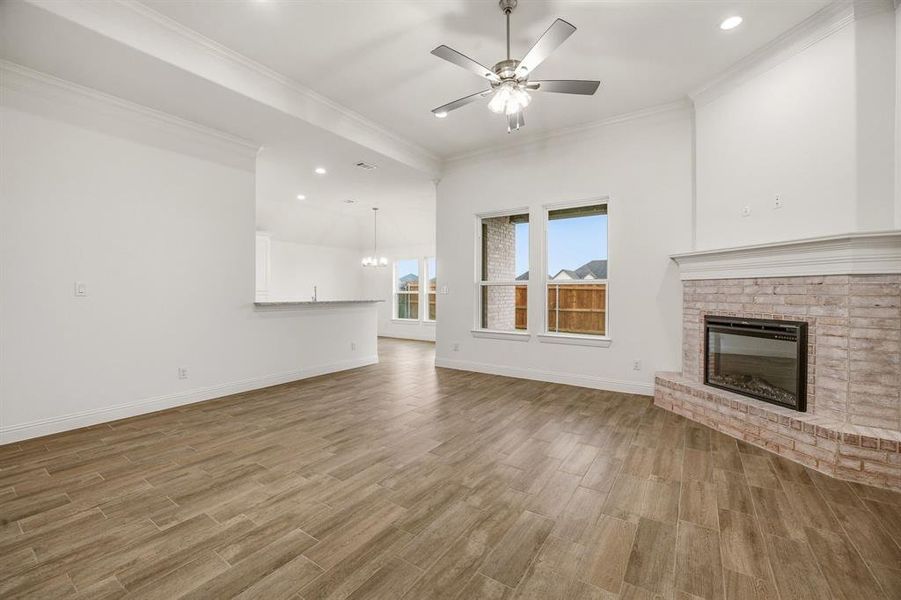 The living area features wood-look tile flooring, a corner fireplace with a light brick surround, and windows providing outdoor views