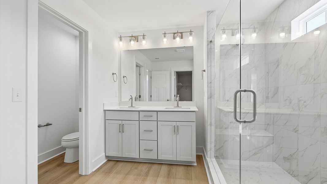 Highly functional and elegant en-suite with dual vanities, tiled walk-in shower, and refined finishes