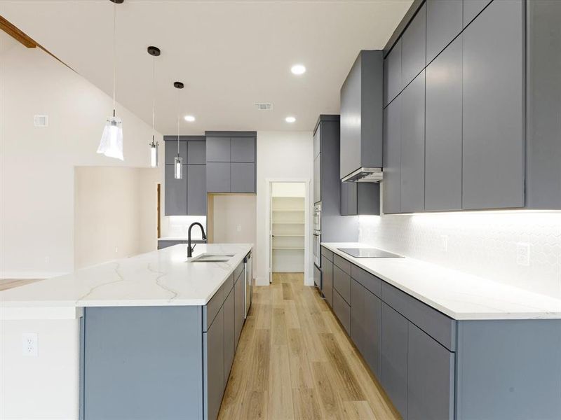 Kitchen featuring modern cabinets, gray cabinets, pendant lighting, and light wood-style floors