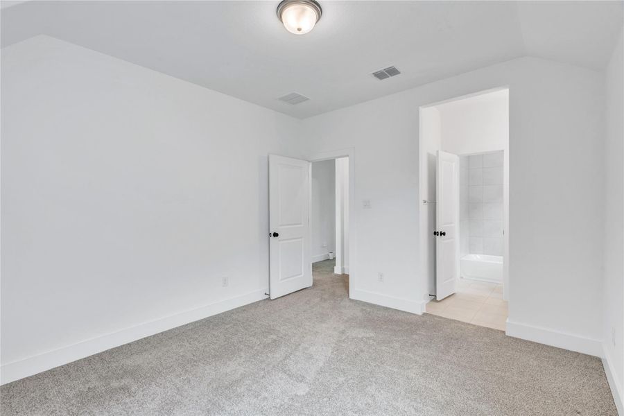 A well-lit bedroom features plush carpeting and convenient access to an en-suite bath.
