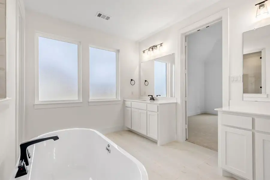 Full bath with a freestanding bath, two vanities, and light tile patterned floors