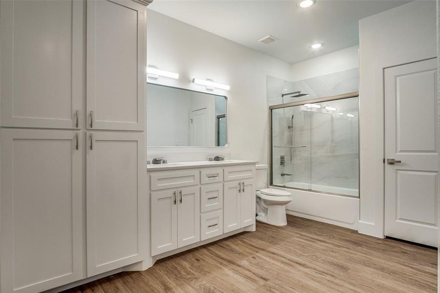 Bathroom featuring combined bath / shower with glass door, double vanity, light wood-style floors, and recessed lighting Bathroom featuring combined bath / shower with glass door, double vanity, light wood-style floors, and recessed lighting