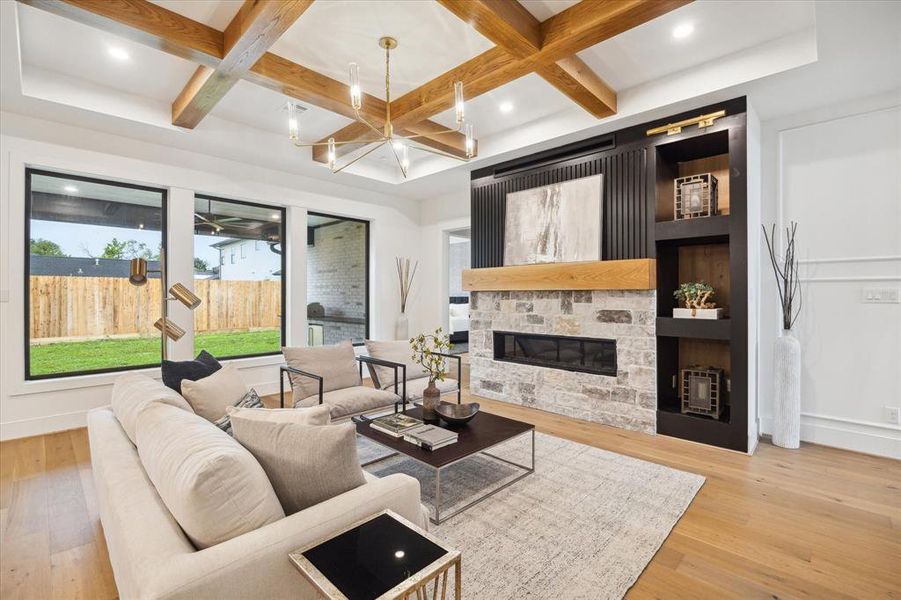 This thoughtfully designed family room showcases an elongated fireplace perfectly positioned against a stone and wood backdrop with a mantle, accented by built-ins.