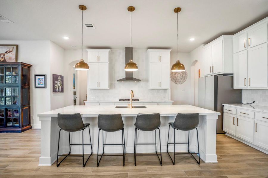 Modern kitchen with a spacious island, sleek pendant lights, equipped wtih stainless steel appliances, ample cabinetry, and wood flooring, creating the perfect space for the chef in your family.