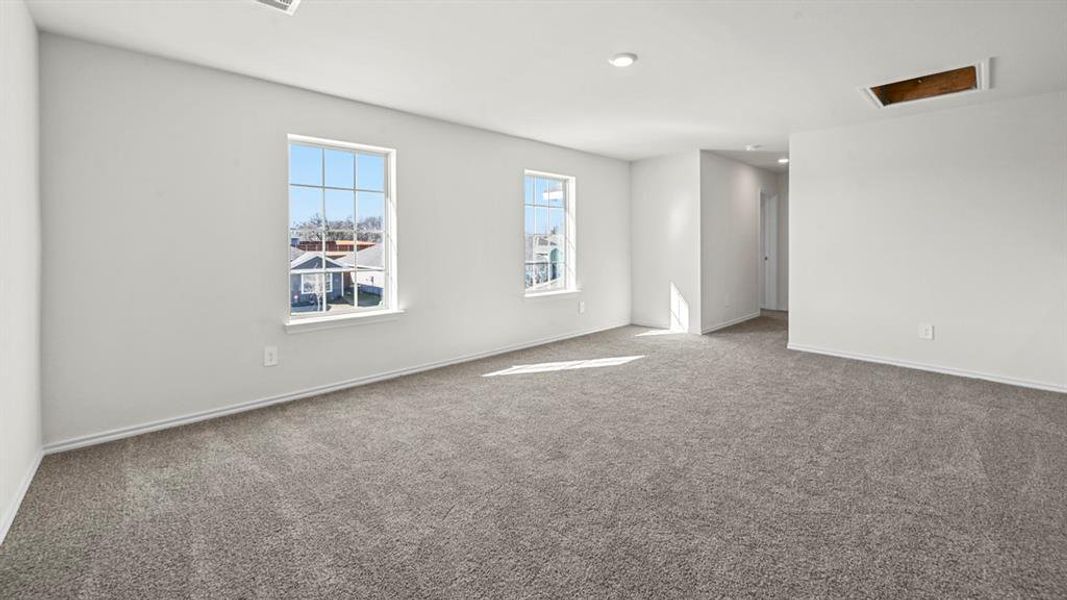 Spacious room featuring neutral carpet, white baseboards, and two large multi-pane windows