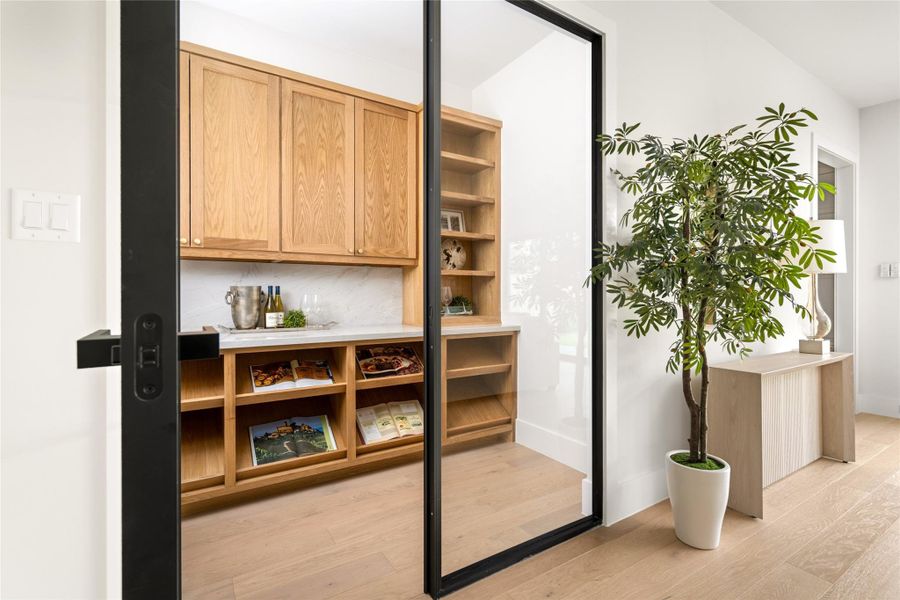 Sophisticated wine room enclosed by a black framed glass door, featuring custom white oak cabinetry, marble backsplash, and ample storage for displaying and storing bottles an elegant statement for entertaining. Sophisticated wine room enclosed by a black framed glass door, featuring custom white oak cabinetry, marble backsplash, and ample storage for displaying and storing bottles an elegant statement for entertaining.