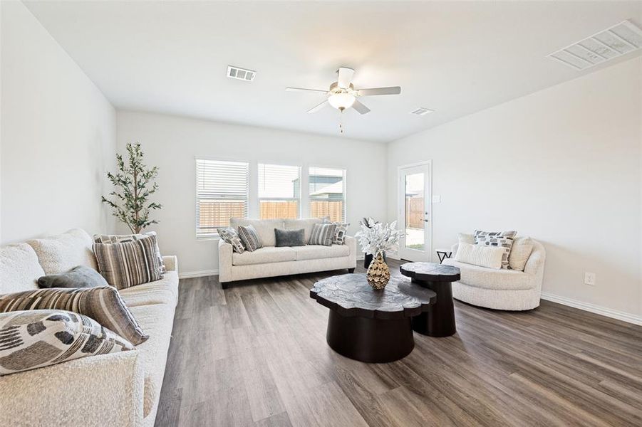 Spacious living area featuring wood-finish flooring, multiple windows, recessed lighting, and a ceiling fan Spacious living area featuring wood-finish flooring, multiple windows, recessed lighting, and a ceiling fan