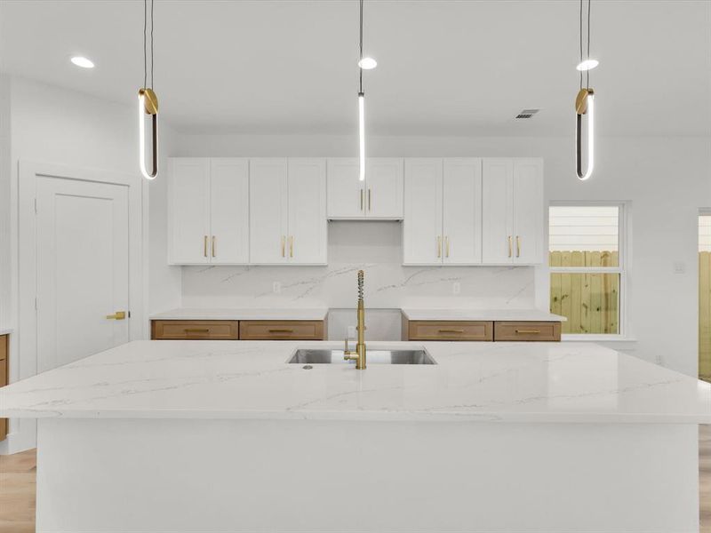 Kitchen with a kitchen island with sink, sink, and hanging light fixtures