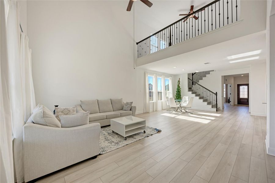 Two-story living area featuring wood-finish flooring and a high vaulted ceiling