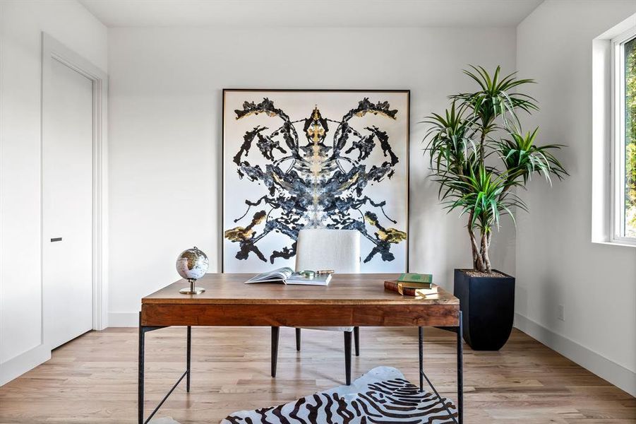 Home office with a wealth of natural light and light hardwood / wood-style floors