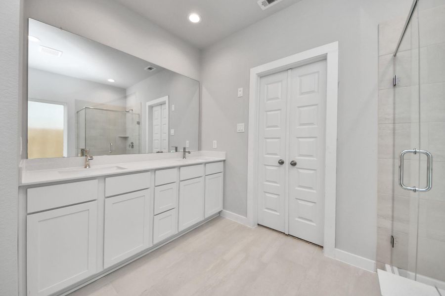 Elevate your daily routine at the elegant vanity, now equipped with double sinks, light countertops, modern hardware, and beautiful recessed lights.