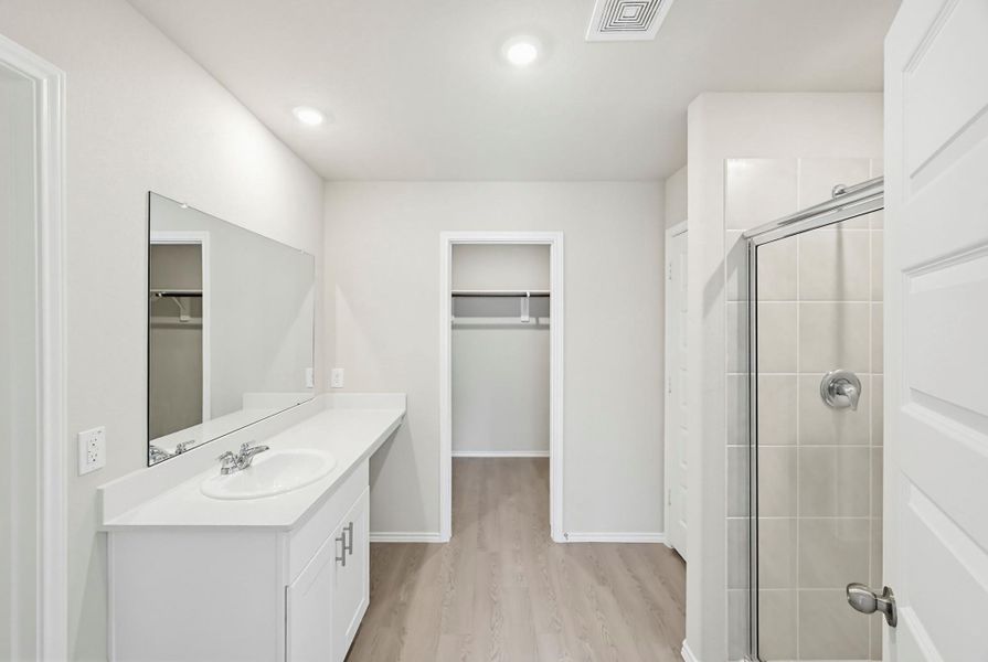 Primary bath complete with Silestone vanity and oversized mirror while the sleek tile shower adds a fresh finish.