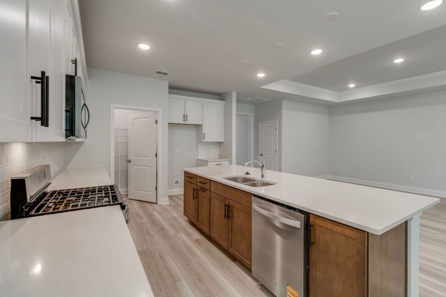 Gourmet Kitchen with decorative lighting with white cabinets and a dark island.