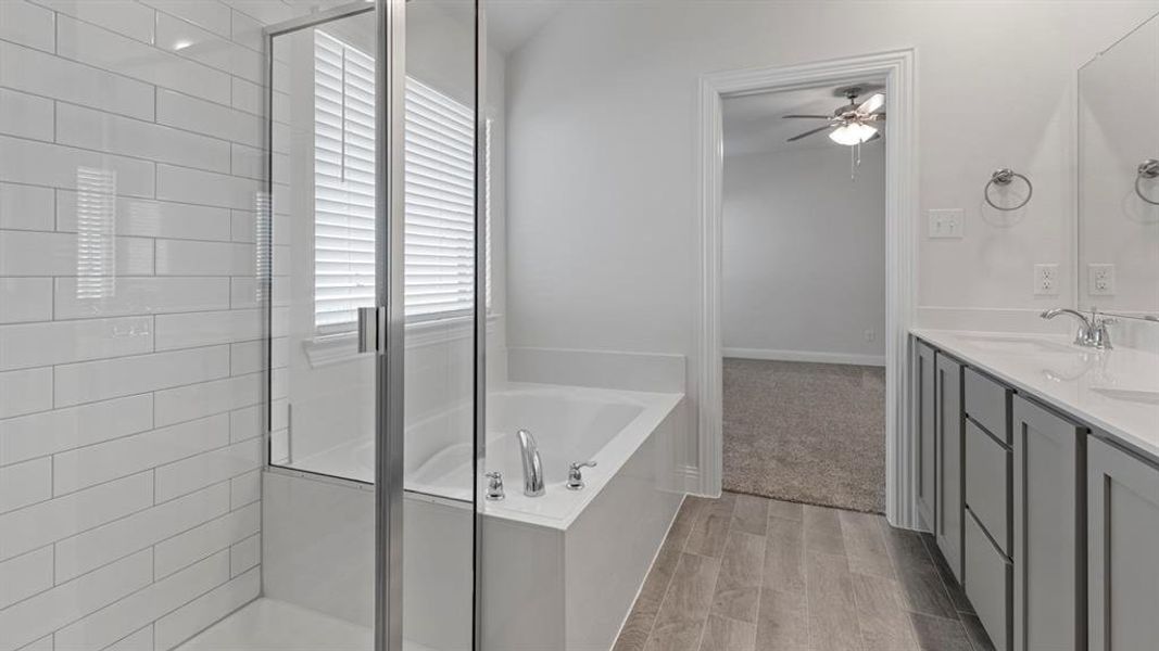 Bathroom with a garden tub, double vanity, a stall shower, and wood finish floors