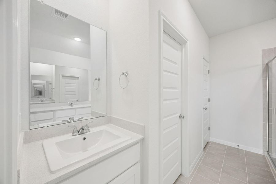 Bathroom with tiled shower, vanity, and tile patterned flooring
