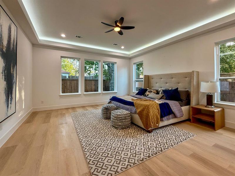 Bedroom featuring a tray ceiling, light wood finished floors, ceiling fan, and recessed lighting