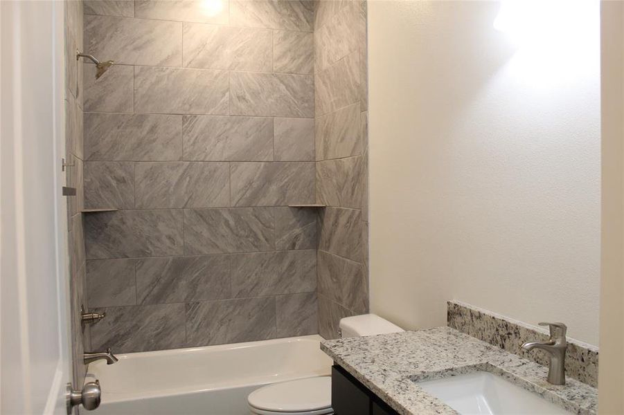 Full bathroom featuring vanity, toilet, and tiled shower / bath