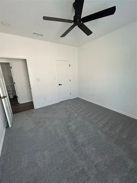 Unfurnished bedroom with dark carpet and a ceiling fan